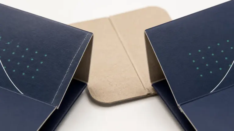 Folding carton crease cracking shown beside a clean scored fold on printed paperboard.