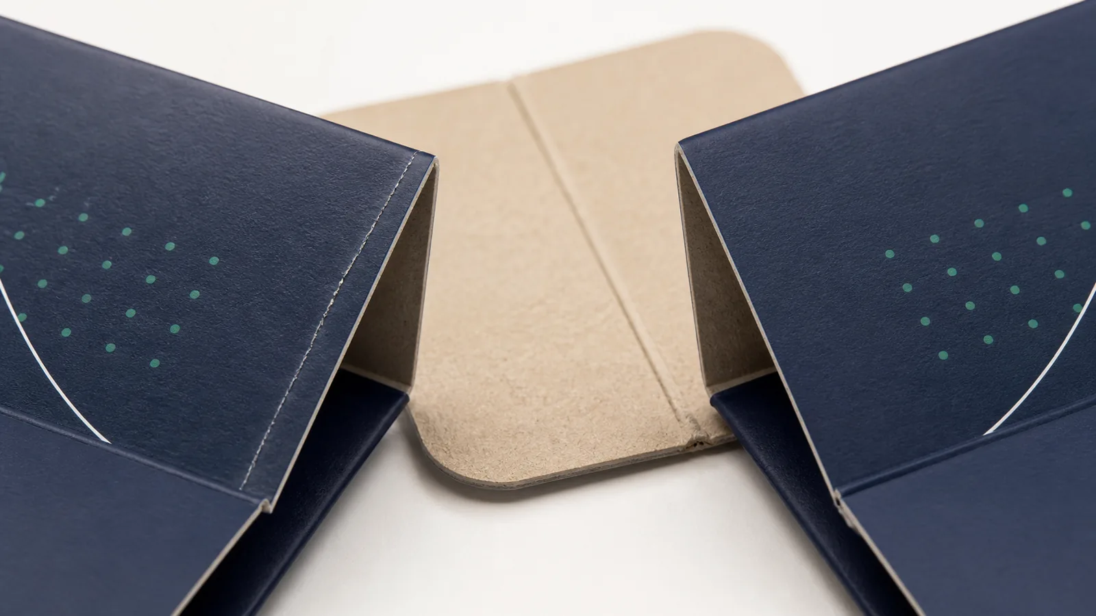 Folding carton crease cracking shown beside a clean scored fold on printed paperboard.